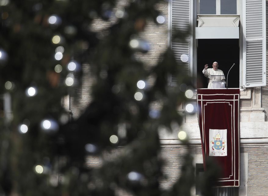 Framed by a Christmas tree, Pope Francis waves during the Angelus noon prayer from his studio window overlooking St. Peter's Square at the Vatican, Sunday, Dec. 9, 2018. (AP Photo/Alessandra Tarantino)