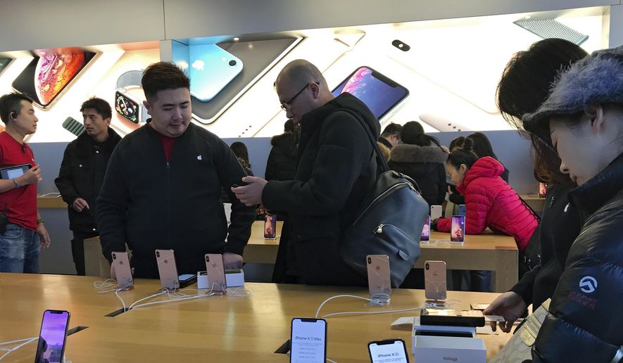 People buy the latest iPhone while others try out its latest model at an Apple Store in Beijing, Tuesday, Dec. 11, 2018. (AP Photo/Andy Wong) ** FILE **