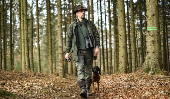 In this Dec. 7, 2018 photo Dirk Gratzel walks with his dog at his hunting ground in Stollberg, western Germany. Gratzel counts his carbon emissions. The software entrepreneur from Germany is among a growing number of people looking for ways to cut their personal greenhouse gas emissions from levels that scientists say are unsustainable if global warming is to be curbed.  (AP Photo/Martin Meissner)