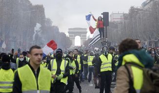 In this Nov. 24, 2018, file photo, demonstrators march on the famed Champs-Elysees avenue in Paris, France, as they protest the rising of the fuel prices. “Yellow vest” protests have gripped France for four weeks, blocking highways from Provence to Normandy and erupting in rioting in Paris. They’ve shaken the country to its core and left President Emmanuel Macron struggling to retain control. (AP Photo/Kamil Zihnioglu, File)
