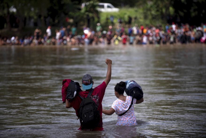 A migrant raises his fist as he nears the Mexican side of the the Suchiate River, that connects Guatemala and Mexico, Monday, Oct. 29, 2018. (AP Photo/Santiago Billy)