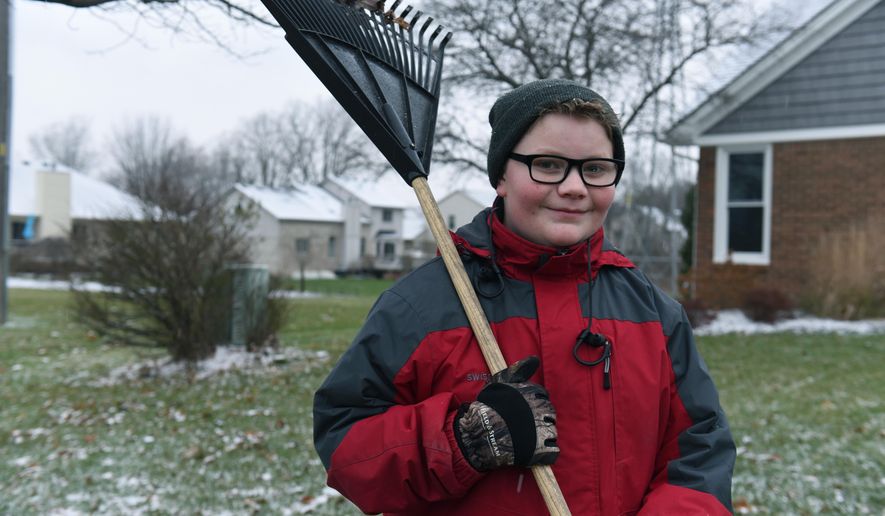 In this Thursday, Nov. 29, 2018 photo, Kaleb Klakulak takes a break from raking leaves outside the home a home in Rochester Hills, Mich., as he raises money for a headstone for his best friend Kenneth "K.J." Gross, who died of cancer last year. (Max Ortiz/Detroit News via AP)