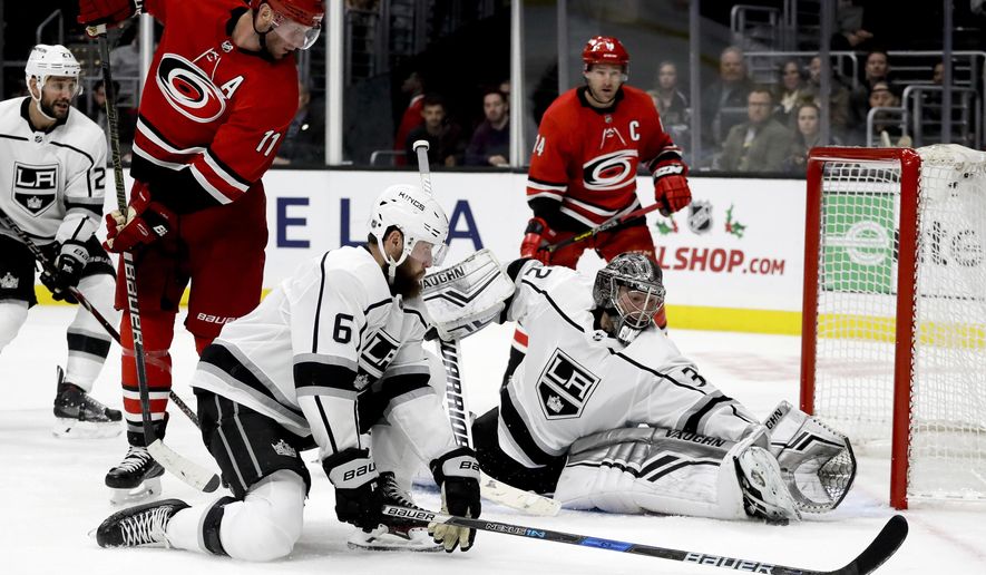 Los Angeles Kings goaltender Jonathan Quick blocks shot by Carolina Hurricanes center Jordan Staal as defenseman Jake Muzzin looks on during the third period of an NHL hockey game in Los Angeles, Sunday, Dec. 2, 2018. The Kings won 2-0. (AP Photo/Chris Carlson)