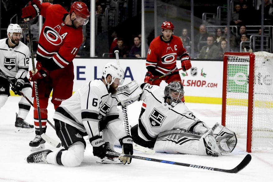 Los Angeles Kings goaltender Jonathan Quick blocks shot by Carolina Hurricanes center Jordan Staal as defenseman Jake Muzzin looks on during the third period of an NHL hockey game in Los Angeles, Sunday, Dec. 2, 2018. The Kings won 2-0. (AP Photo/Chris Carlson)