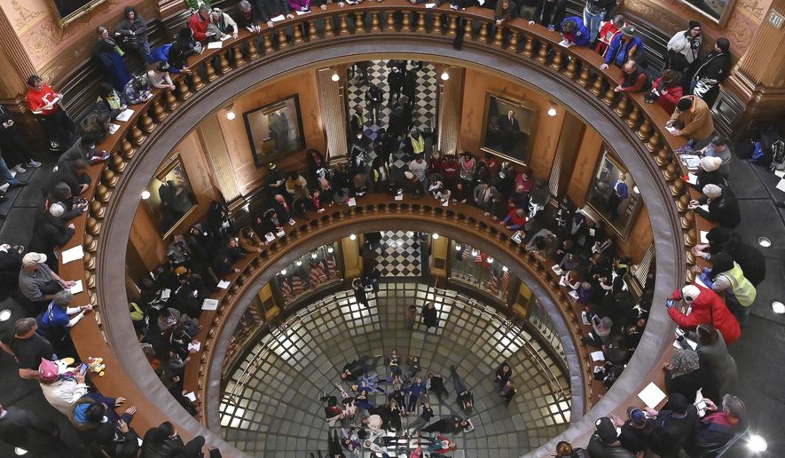 A group of school children visiting the Capitol lie on the floor of the Rotunda while demonstrators make noise and chant as Tthe Michigan Senate and House of Representatives consider bills during a "lame duck" session in Lansing, Mich., Wednesday, Dec 12, 2019. Michigan Republicans moved Wednesday to curtail ballot initiatives by advancing a measure limiting how many signatures could come from any one region of the state, the latest proposal assailed by critics as an unconstitutional, lame-duck power grab from incoming Democratic officeholders or voters. (Dale G.Young/Detroit News via AP)