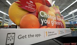 In this Nov. 9, 2018, file photo a sign promotes online and home delivery of groceries at a Walmart Supercenter  in Houston.  (AP Photo/David J. Phillip, File) **FILE**