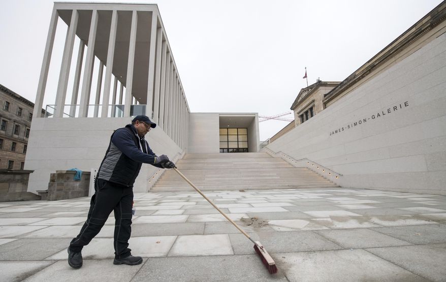 A worker cleans the square in fron of the new James Simon Gallery in Berlin Thursday, Dec. 13, 2018. Berlin has completed a new addition to its Museum Island complex aimed at completing the ensemble of popular museums and making it more user-friendly. (Bernd von Jutrczenka/dpa via AP)