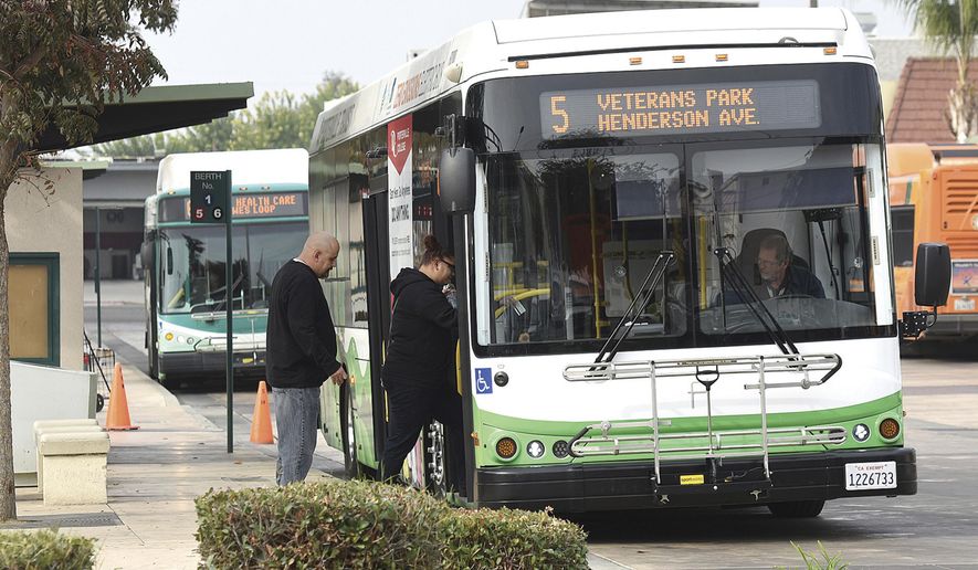 FILE - In this Nov. 16, 2018, file photo, commuters ride a new zero emission electric buses in Porterville, Calif. The California Air Resources Board voted Friday, Dec. 14, 2018, to require that all new buses be carbon-free by 2029. Environmental advocates project that the last dirty buses will phase out by 2040. (Chieko Hara/The Porterville Recorder via AP, FIle)