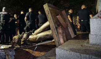 FILE - In this Monday, Aug. 20, 2018, file photo, police stand guard after the Confederate statue known as Silent Sam was toppled by protesters on campus at the University of North Carolina in Chapel Hill, N.C. The board overseeing North Carolina’s public universities is meeting to decide the fate of &amp;quot;Silent Sam.&amp;quot;  The University of North Carolina System Board of Governors was meeting Friday, Dec. 14, to discuss a proposal to build a $5 million building to house the statue at UNC-Chapel Hill.  (AP Photo/Gerry Broome, File)