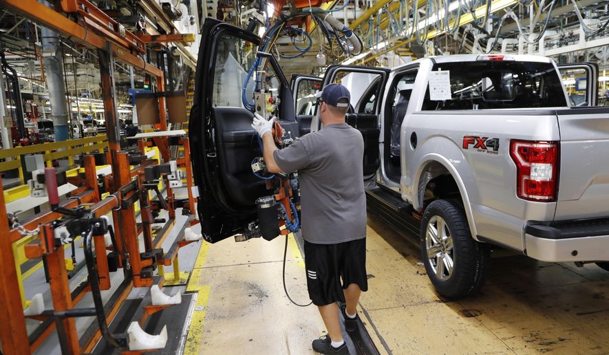FILE- In this Sept. 27, 2018, file photo a United Auto Workers assemblyman installs the front doors on a 2018 Ford F-150 truck being assembled at the Ford Rouge assembly plant in Dearborn, Mich. On Friday, Dec. 14, the Federal Reserve reports on U.S. industrial production for November. (AP Photo/Carlos Osorio, File)