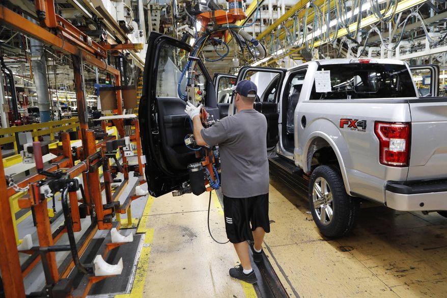 FILE- In this Sept. 27, 2018, file photo a United Auto Workers assemblyman installs the front doors on a 2018 Ford F-150 truck being assembled at the Ford Rouge assembly plant in Dearborn, Mich. On Friday, Dec. 14, the Federal Reserve reports on U.S. industrial production for November. (AP Photo/Carlos Osorio, File)