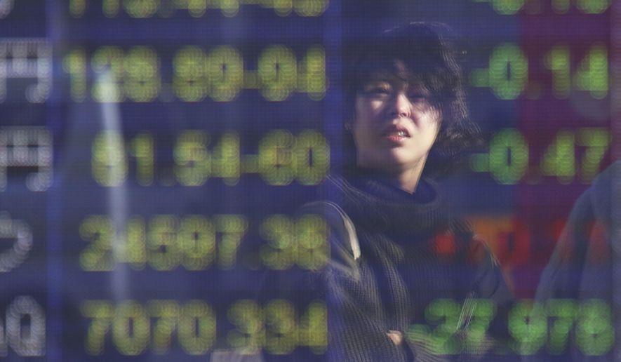 A woman is reflected on the electronic board of a securities firm in Tokyo, Friday, Dec. 14, 2018. Asian markets tumbled on Friday after China reported weaker-than-expected economic data, stirring up worries about the state of the world's second largest economy. (AP Photo/Koji Sasahara)