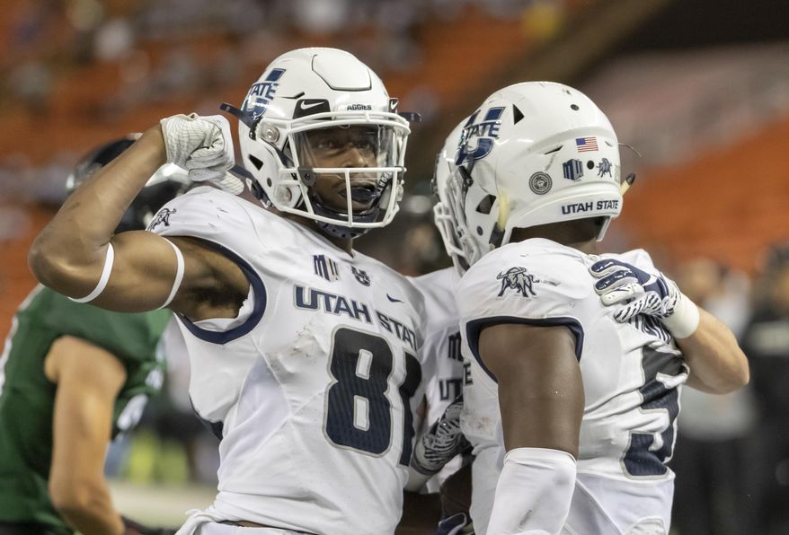 FILE - In this Saturday, Nov. 3, 2018 file photo, Utah State wide receiver Savon Scarver (81) celebrates a touchdown run by his teammate running back Darwin Thompson (5) in the second half of an NCAA college football game against Hawaii in Honolulu. The high-flying offenses of Utah State and North Texas meet in the New Mexico Bowl in what is expected to be a passing attack shootout. Utah State is making its seventh college postseason appearance in eight years while North Texas tries to give head coach Seth Littrell his first bowl victory. (AP Photo/Eugene Tanner, File)
