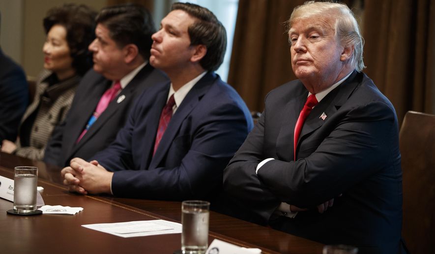 President Donald Trump listens to a question from a reporter during a meeting with newly elected governors in the Cabinet Room of the White House, Thursday, Dec. 13, 2018, in Washington. From left, Secretary of Transportation Elaine Chao, Governor-elect J.B. Pritzker, D-Ill., Governor-elect Ron DeSantis, R-Fla., and Trump. (AP Photo/Evan Vucci)