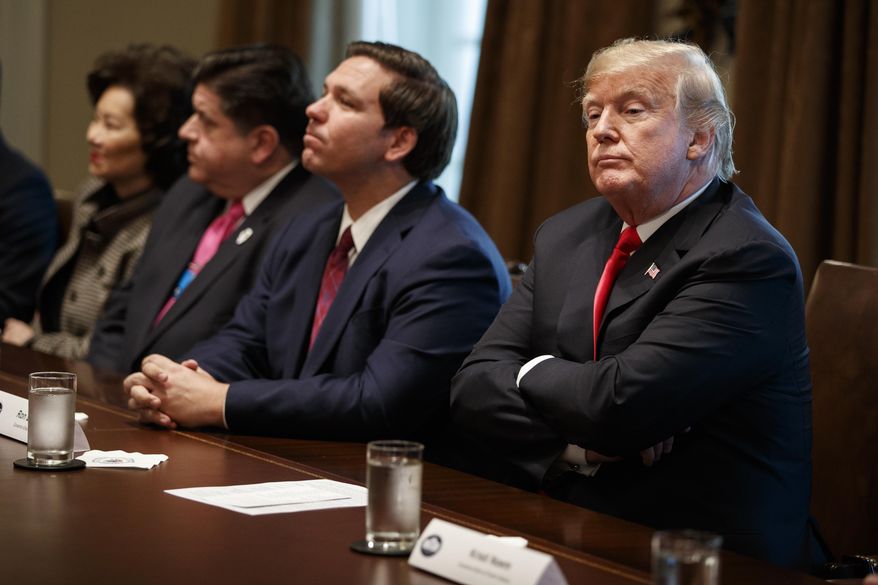 President Donald Trump listens to a question from a reporter during a meeting with newly elected governors in the Cabinet Room of the White House, Thursday, Dec. 13, 2018, in Washington. From left, Secretary of Transportation Elaine Chao, Governor-elect J.B. Pritzker, D-Ill., Governor-elect Ron DeSantis, R-Fla., and Trump. (AP Photo/Evan Vucci)