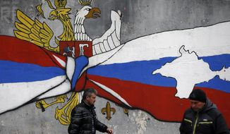 People walk by the graffiti that shows Serbian, left, and Russian flags with maps of Kosovo and Crimea in northern, Serb-dominated part of ethnically divided town of Mitrovica, Kosovo, Saturday, Dec. 15, 2018. Serbia threatened a possible armed intervention in Kosovo after the Kosovo parliament on Friday overwhelmingly approved the formation of a regular army, and Russia denounced the move. (AP Photo/Darko Vojinovic)