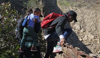 Honduran migrants cross the U.S. border wall to San Diego, California from Tijuana, Mexico, Sunday, Dec. 16, 2018, before turning themselves in to U.S. border patrol agents. (AP Photo/Moises Castillo)