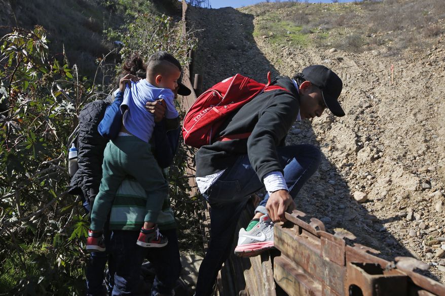 Honduran migrants cross the U.S. border wall to San Diego, California from Tijuana, Mexico, Sunday, Dec. 16, 2018, before turning themselves in to U.S. border patrol agents. (AP Photo/Moises Castillo)