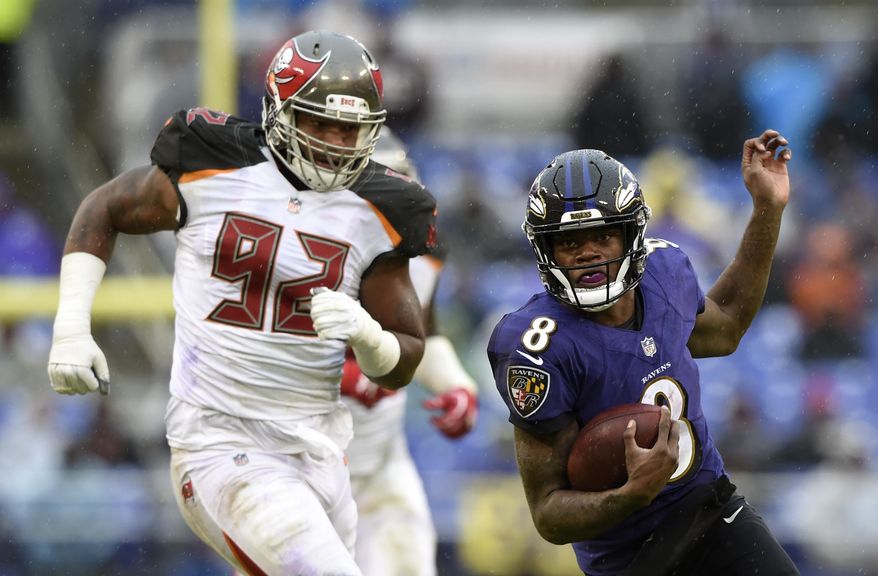 Baltimore Ravens quarterback Lamar Jackson, right, rushes past Tampa Bay Buccaneers defensive tackle William Gholston in the second half of an NFL football game, Sunday, Dec. 16, 2018, in Baltimore. (AP Photo/Gail Burton)