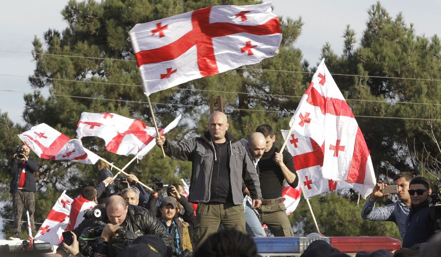 Supporters of opposition candidate Grigol Vashadze wave Georgian national flags during their protest against the new Georgian President Salome Zurabishvili's inauguration outside Telavi, Georgia, Sunday, Dec. 16, 2018. Zurabishvili, a French-born former Georgian foreign minister, was sworn in as Georgian first female president on Sunday. (AP Photo/Shakh Aivazov)