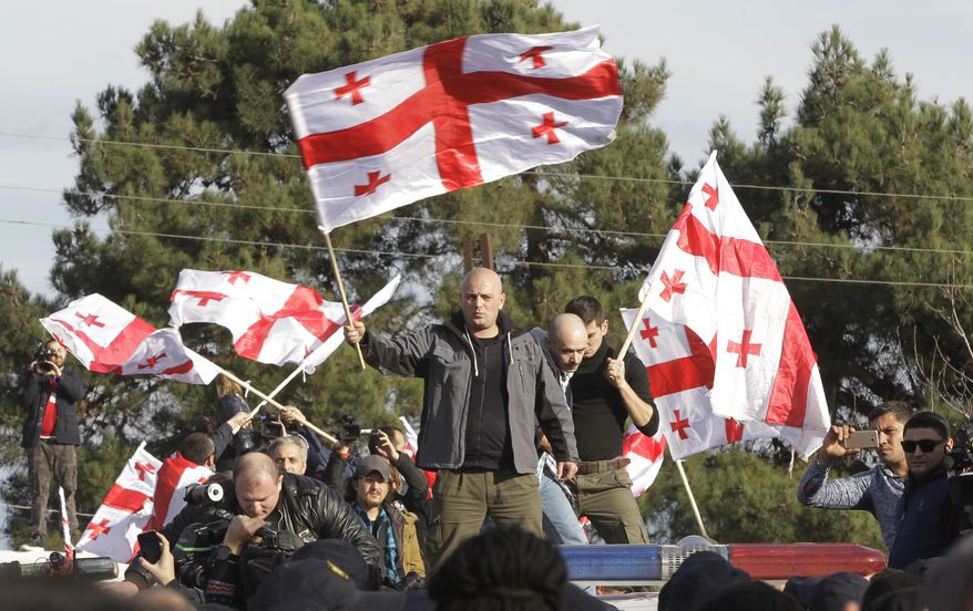 Supporters of opposition candidate Grigol Vashadze wave Georgian national flags during their protest against the new Georgian President Salome Zurabishvili's inauguration outside Telavi, Georgia, Sunday, Dec. 16, 2018. Zurabishvili, a French-born former Georgian foreign minister, was sworn in as Georgian first female president on Sunday. (AP Photo/Shakh Aivazov)