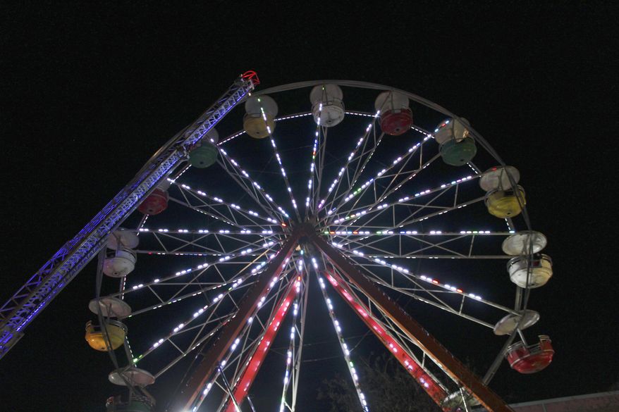 In this Saturday, Dec. 15, 2018 photo, firefighters work to disembark passengers from a Ferris wheel that malfunctioned in downtown Conway, Ark. A pivot pin holding one of the Ferris wheel's cylinders in place broke. All passengers were safely rescued. (Jeanette Anderton/Log Cabin Democrat via AP)