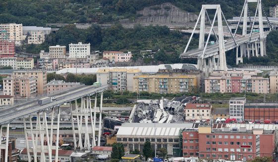 FILE - In this Tuesday, Aug. 14, 2018 file photo cars are blocked on the Morandi highway bridge after a section of it collapsed, in Genoa, northern Italy. A large section of the bridge collapsed over an industrial area in the Italian city of Genova during a sudden and violent storm, leaving vehicles crushed in rubble below. (AP Photo/Antonio Calanni, File)