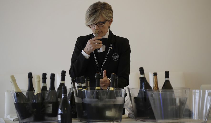 In this image taken on Monday, Oct. 15, 2018, a sommelier opens Prosecco bottles during a wine testing in Asolo, Italy. Global sales of prosecco the smooth, drinkable sparkling wine rooted in the northeastern hills of Italy are booming, and champagne, the original bubbly, is taking note. (AP Photo/Luca Bruno)