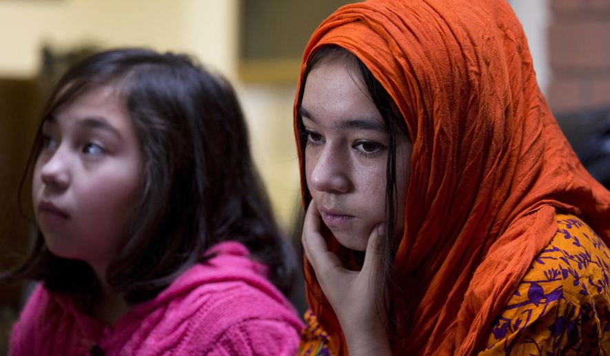 In this Nov. 29, 2018 photo, Shahnaz, 16, right, and Shakeela, 12, daughters of Mir Aman, speak to The Associated Press, in Islamabad, Pakistan. Scores of Pakistani men like Aman, whose Muslim Uighur wives have disappeared into internment camps in China, feel helpless, fighting a wall of silence as they struggle to reunite their families. Political and economic factors, including concerns about losing out on vast Chinese investments, have kept Muslim countries like Pakistan quiet about the plight of their fellow Muslims, being weaned off their faith in so-called re-education camps. (AP Photo/B.K. Bangash)