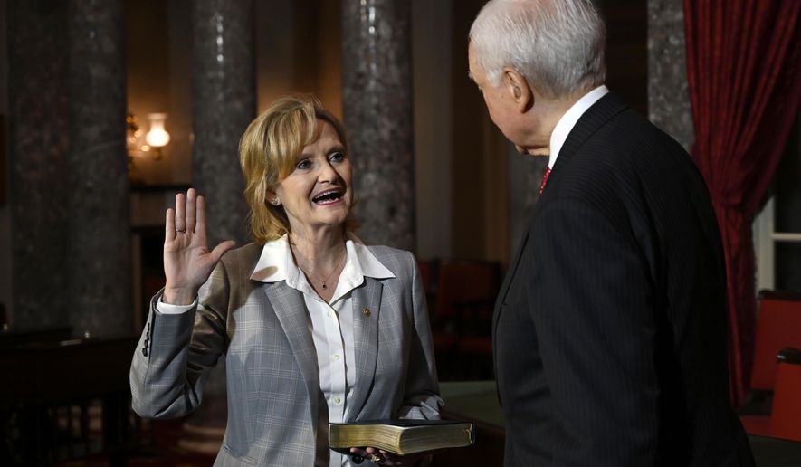 Sen. Cindy Hyde-Smith, R-Miss., left, stands with Sen. Orrin Hatch, R-Utah, right, during a ceremonial swearing-in on Capitol Hill in Washington, Monday, Dec. 17, 2018. (AP Photo/Susan Walsh)