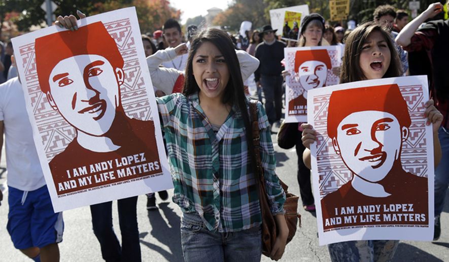 FILE - In this Oct. 29, 2013 file photo, protesters hold images of shooting victim Andy Lopez during a march in Santa Rosa, Calif. Sonoma County will pay $3 million to settle a civil rights lawsuit filed by the family of a California teenager who was fatally shot by a sheriff's deputy while holding a pellet gun. The Press Democrat reports the settlement was approved unanimously Tuesday, Dec. 18, 2018, by the county Board of Supervisors, bringing to a close a lawsuit filed in Nov. 2013 by the family of 13-year-old Lopez. (AP Photo/Marcio Jose Sanchez, File)