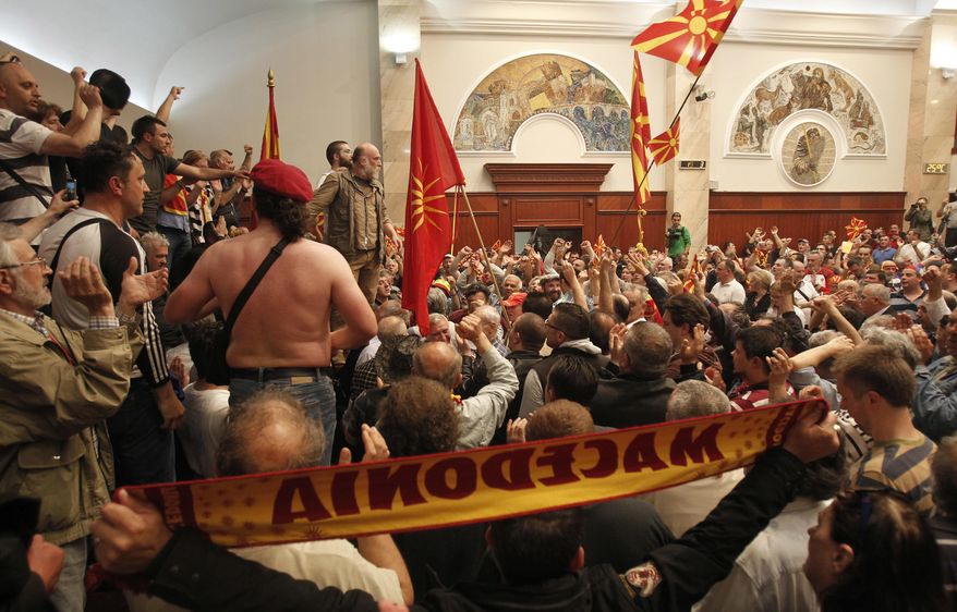 FILE - In this April 27, 2017 file photo, protesters enter the parliament building in Skopje, Macedonia. Scores broke through a police cordon to protest the election of a new speaker despite a months-long deadlock in talks to form a new government. Macedonian lawmakers approved on Tuesday, Dec. 18, 2018, a law offering amnesty to some suspected perpetrators of the violent storming of parliament last year, seeking to boost reconciliation in a deeply polarized society. (AP Photo/Boris Grdanoski, File)
