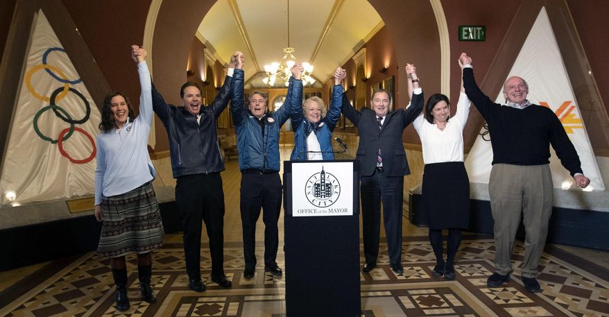 Salt Lake City Council Chairwoman Erin Mendenhall, Fraser Bullock, chief operating officer of the 2002 Winter Games, Jeff Robbins, president and CEO of the Utah Sports Commission, Salt Lake City Mayor Jackie Biskupski, Gov. Gary Herbert, USA Olympic speed skater Catherine Rainey-Norman and Salt Lake County Councilman Jim Bradley raise their arms in celebration after the USOC choose Salt Lake over Denver to bid on behalf of the U.S. for future Winter Games, Friday, Dec. 14, 2018 in Salt Lake City. Salt Lake City got the green light to bid for the Winter Olympics — most likely for 2030 — in an attempt to bring the Games back to the city that hosted in 2002 and provided the backdrop for the U.S. winter team's ascendance into an international powerhouse. (Steve Griffin/The Deseret News via AP)