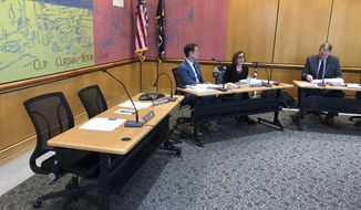 Gov. Kate Brown, middle, speaks on Tuesday, Dec. 18, 2018, at an Oregon State Land Board meeting in Salem, Ore. Secretary of State Dennis Richardson&#x27;s desk sits empty at left with him attending via speakerphone. A day earlier, Richardson, who is being treated for brain cancer, reversed his decision to temporarily leave the state land board. The third board member, state Treasurer Tobias Read, is on the right. Next to Brown is Brown&#x27;s natural resources policy manager, Jason Miner. (AP Photo/Andrew Selsky)
