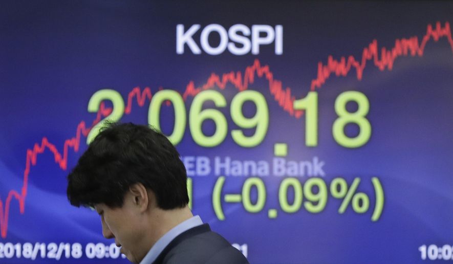 A currency trader walks by the screen showing the Korea Composite Stock Price Index (KOSPI) at the foreign exchange dealing room in Seoul, South Korea, Tuesday, Dec. 18, 2018. Asian stocks fell on Tuesday, tracking losses on Wall Street as traders braced for an interest rate hike by Federal Reserve. (AP Photo/Lee Jin-man)