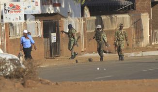 FILE - In this Aug, 1, 2018 file photo, soldiers patrol the streets in Harare, Zimbabwe, following demonstrations by opposition party supporters. Zimbabwe Military and police were responsible for killing six people when they intervened to stop post election election protests in the capital in August, according to a report by a commission of inquiry released Tuesday, Dec. 18, 2018. (AP Photo/Tsvangirayi Mukwazhi)