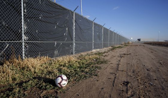 A soccer ball rest next to the tarp covered fence outside the Tornillo detention camp for migrants in Tornillo, Texas, Thursday Dec. 13, 2018. The Trump administration announced in June 2018 that it would open the temporary shelter for up to 360 migrant children in this isolated corner of the Texas desert. Less than six months later, the facility has expanded into a detention camp holding thousands of teenagers, showing every sign of becoming more permanent. (AP Photo/Andres Leighton)