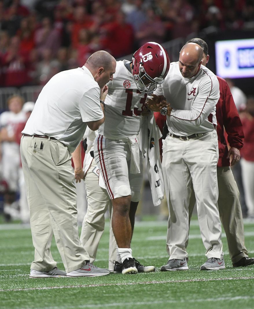 FILE - In this Dec. 1, 2018, file photo, Alabama quarterback Tua Tagovailoa (13) is helped by medical staff during the second half of the Southeastern Conference championship NCAA college football game against Georgia, in Atlanta. Tagovailoa is optimistic that he will be fully recovered from ankle surgery and ready to play in the Orange Bowl. The Alabama quarterback and Heisman Trophy runner-up said his left ankle will be just fine for the College Football Playoff semifinal game with Oklahoma on Dec. 29. “I'll probably be at 100 percent by the time the game comes,” Tagovailoa said Wednesday, Dec. 19, 2018. “That's my prediction. Definitely.” (AP Photo/John Amis, File)