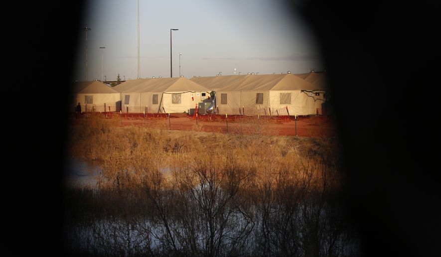 Tents are seen through a hole in the tarp that covers the fence of the Tornillo detention camp for migrant teens in Tornillo, Texas, Thursday, Dec. 13, 2018. At this unlicensed tent city in the Texas desert that is housing children who are closest to being released, the population dipped down to just over 1,000 children in late October, when human rights groups toured the camp. By Dec. 17, the population reached 2,745. (AP Photo/Andres Leighton)
