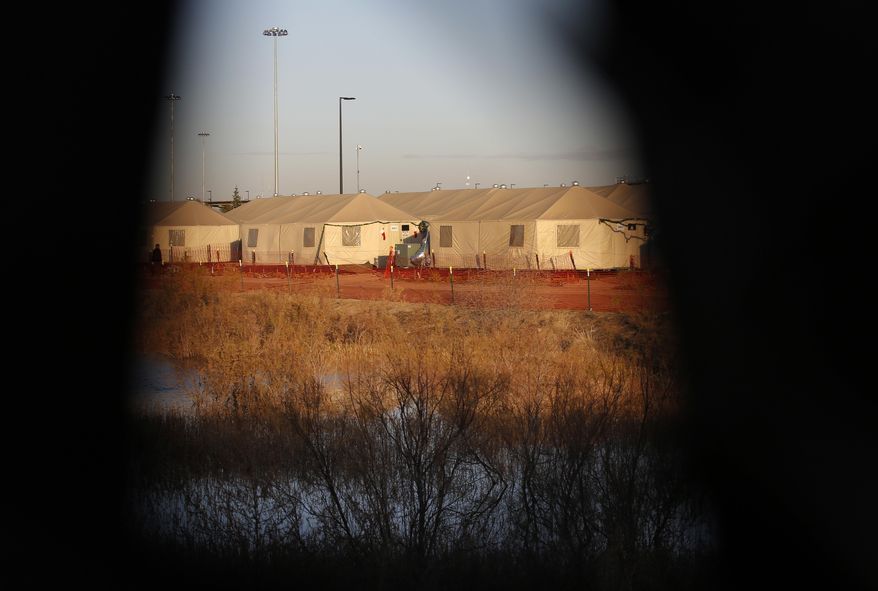 Tents are seen through a hole in the tarp that covers the fence of the Tornillo detention camp for migrant teens in Tornillo, Texas, Thursday, Dec. 13, 2018. At this unlicensed tent city in the Texas desert that is housing children who are closest to being released, the population dipped down to just over 1,000 children in late October, when human rights groups toured the camp. By Dec. 17, the population reached 2,745. (AP Photo/Andres Leighton)
