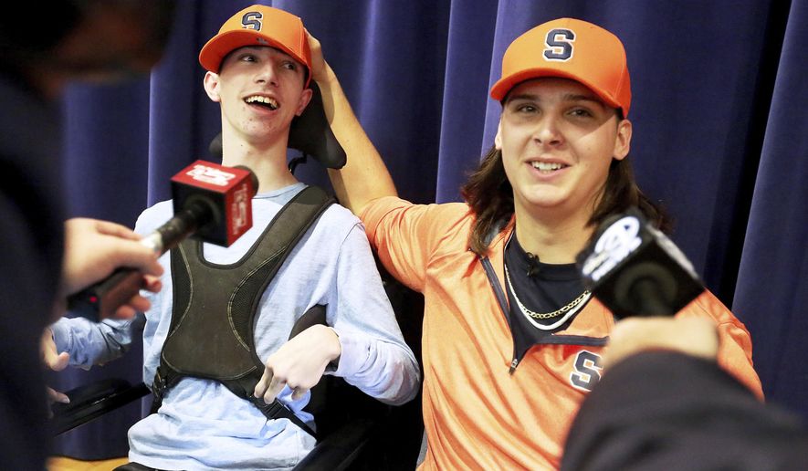 Hanahan High School football player Cooper Dawson, right, talks to the media after first letting his friend and fellow senior Kingsley Feiman announce that he would play football at Syracuse University on early signing day in Hanahan, S.C., Wednesday, Dec. 19, 2018. (Brad Nettles//The Post And Courier via AP)