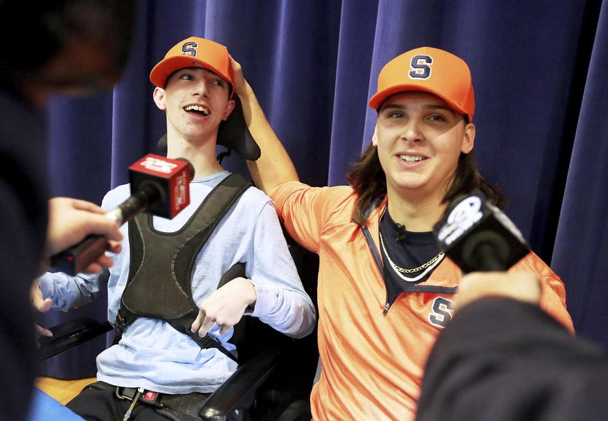 Hanahan High School football player Cooper Dawson, right, talks to the media after first letting his friend and fellow senior Kingsley Feiman announce that he would play football at Syracuse University on early signing day in Hanahan, S.C., Wednesday, Dec. 19, 2018. (Brad Nettles//The Post And Courier via AP)