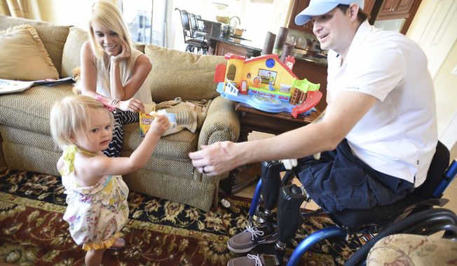 FILE--In this AprIl 1, 2015, file photo, retired Air Force Airman Brian Kolfage, right, gives a piece of cheese to his one-year-old daughter Paris Kolfage as his wife Ashley Kolfage looks on at their recently rented home in Sandestin, Fla. Kolfage, a triple-amputee who lost his limbs serving in Iraq in the U.S. Air Force, started a GoFundMe page to help fund construction of President Donald Trump&#x27;s border wall has already raised millions of dollars.(Nick Tomecek/Northwest Florida Daily News via AP, file)