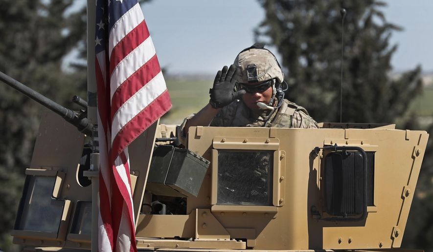 In this April 4, 2018 photo, a U.S. soldier waves as he sits on an armored vehicle, at a road leading to the tense front line with Turkish-backed fighters, in Manbij town, north Syria. President Donald Trump&#39;s decision to withdraw troops from Syria has rattled Washington&#39;s Kurdish allies, who are its most reliable partner in Syria and among the most effective ground forces battling the Islamic State group. Kurds in northern Syria said commanders and fighters met into the night, discussing their response to the surprise announcement Wednesday, Dec. 20, 2018. (AP Photo/Hussein Malla)