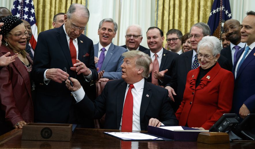 President Donald Trump hands a pen to Sen Chuck Grassley, R-Iowa, after signing criminal justice reform legislation in the Oval Office of the White House, Friday, Dec. 21, 2018, in Washington. Rep. Virginia Foxx, R-N.C, front row, second from right, watches. (AP Photo/Evan Vucci) **FILE**