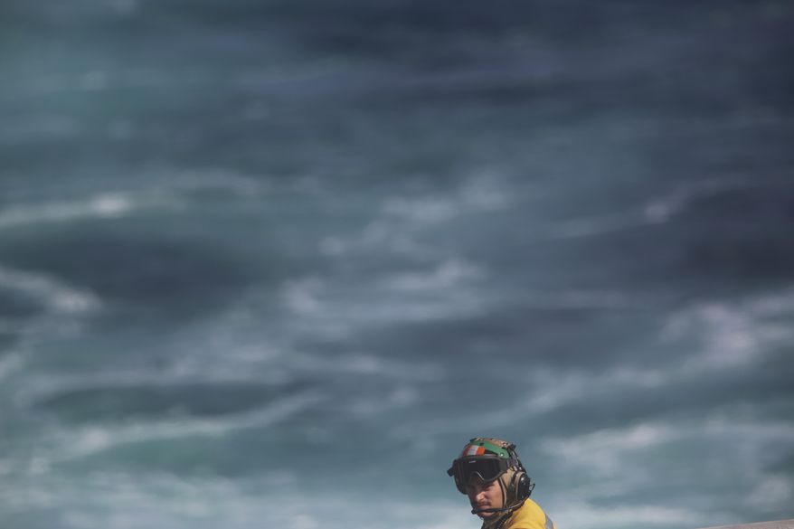 A member of the flight crew of the USS John C. Stennis aircraft carrier watches the flight deck on Friday, Dec. 21, 2018. The U.S. aircraft carrier sailed into the Persian Gulf on Friday, becoming the first since America's withdrawal from the Iran nuclear deal and breaking the longest carrier absence in the volatile region since at least the Sept. 11 terror attacks. (AP Photo/Jon Gambrell)