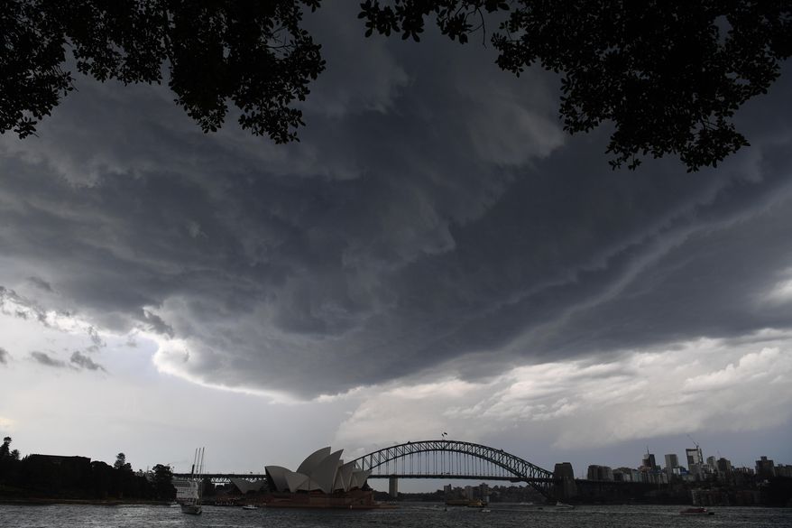 In this Thursday, Dec. 20, 2018, photo, dark storm clouds are seen over the Sydney Opera House and Sydney Harbour Bridge during a hail storm in Sydney. Hailstones the size of tennis and golf balls have damaged homes and thousands of cars around Sydney. The Bureau of Meteorology called the bad weather Thursday evening the "worst hailstorm in 20 years." Some hailstones were 5 to 8 centimeters (2 to 3 1/8 inches) in diameter that fell in western Sydney and its suburbs. (Brendan Esposito/AAP Image via AP)