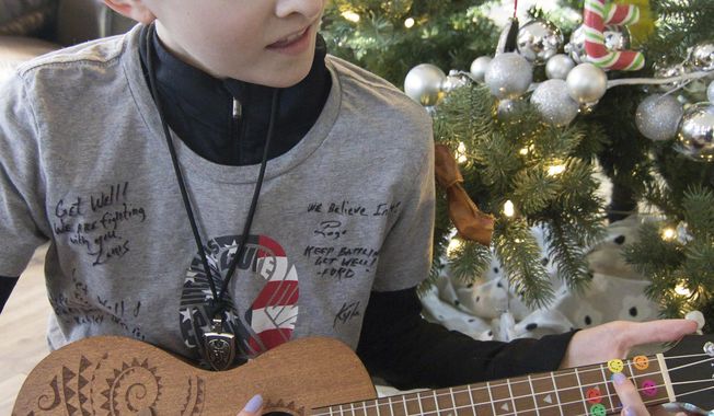 In this Monday, Dec. 17, 2018 photo, 13-year-old Emma Roberts plays the ukulele, a Christmas gift from a friend, just part of an outpouring of love and support she's gotten after being diagnosed with leukemia, in Brighton Township, Mich. (Gillis Benedict/Livingston County Daily Press & Argus via AP)