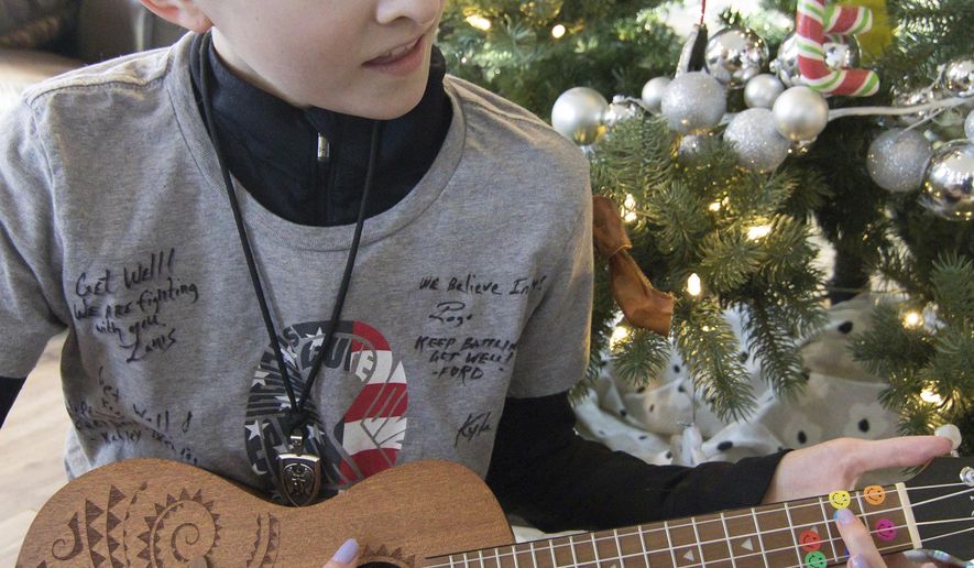 In this Monday, Dec. 17, 2018 photo, 13-year-old Emma Roberts plays the ukulele, a Christmas gift from a friend, just part of an outpouring of love and support she's gotten after being diagnosed with leukemia, in Brighton Township, Mich. (Gillis Benedict/Livingston County Daily Press & Argus via AP)