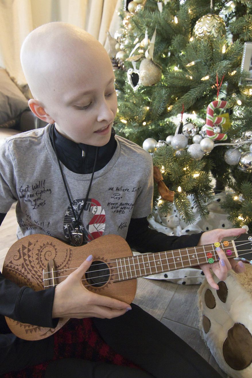 In this Monday, Dec. 17, 2018 photo, 13-year-old Emma Roberts plays the ukulele, a Christmas gift from a friend, just part of an outpouring of love and support she's gotten after being diagnosed with leukemia, in Brighton Township, Mich. (Gillis Benedict/Livingston County Daily Press & Argus via AP)